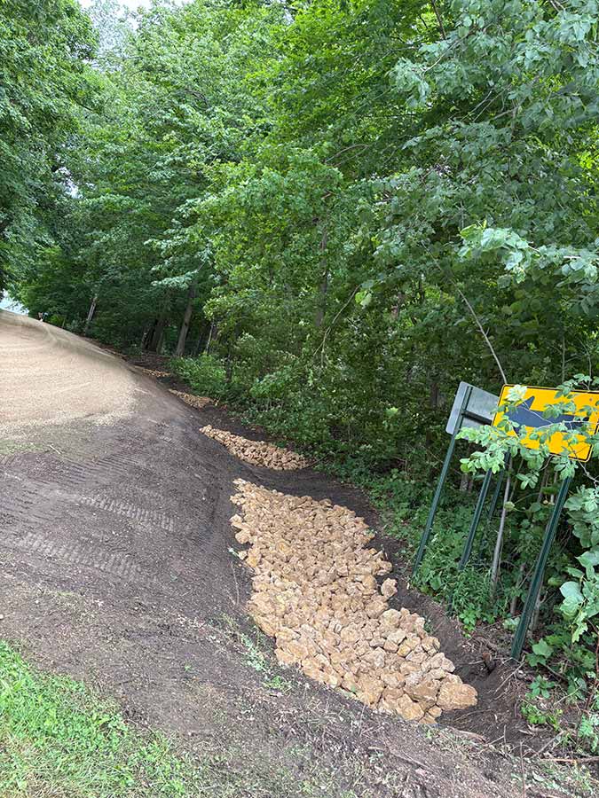 Large rocks fill a drainage ditch to help with stormwater removal.